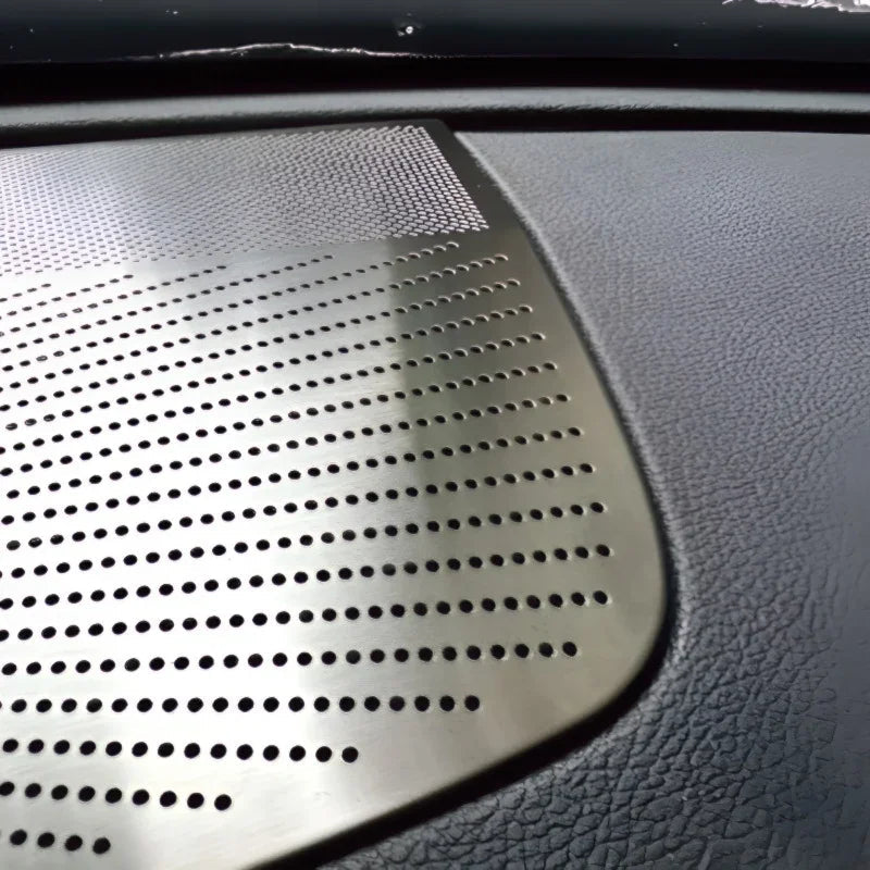 Silver perforated metal trim detail on a dark textured car interior dashboard.