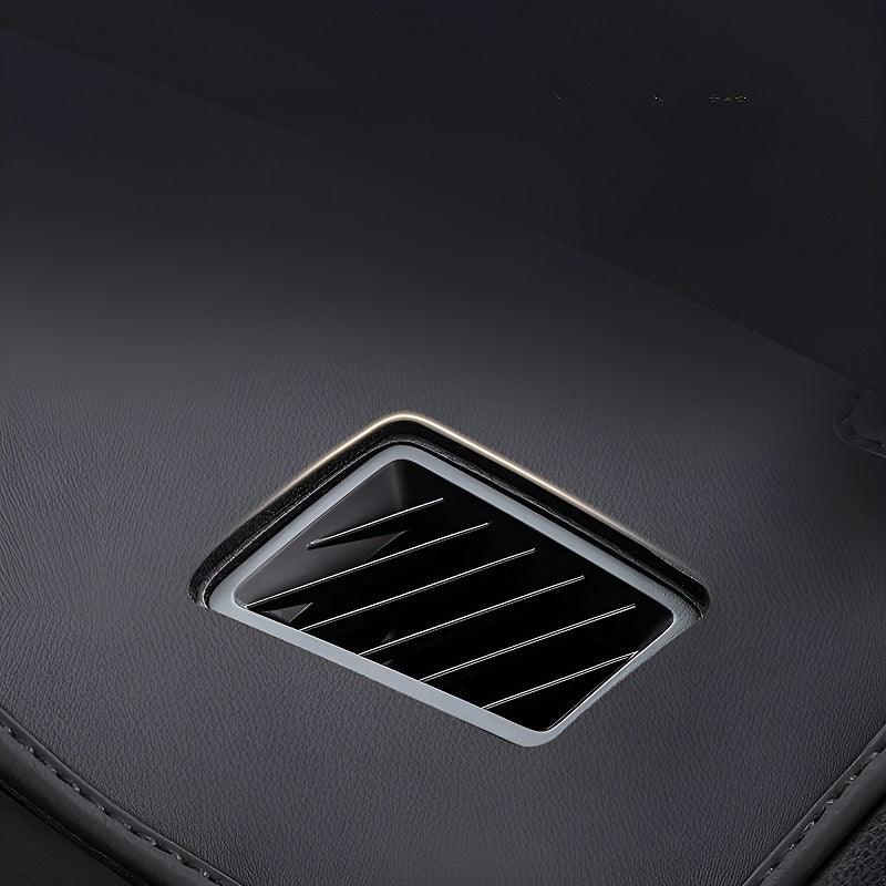 Close-up of a black interior air vent with sleek horizontal slats on a textured dark surface.