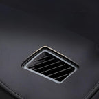 Close-up of a black interior air vent with sleek horizontal slats on a textured dark surface.