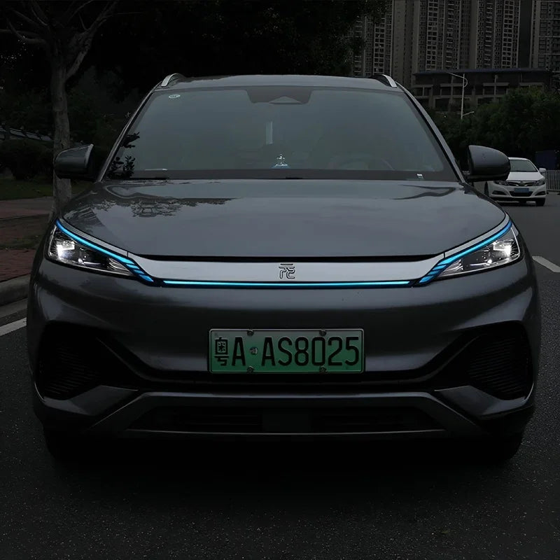 Front view of a grey BYD electric car featuring a distinctive blue LED light strip across the grille.