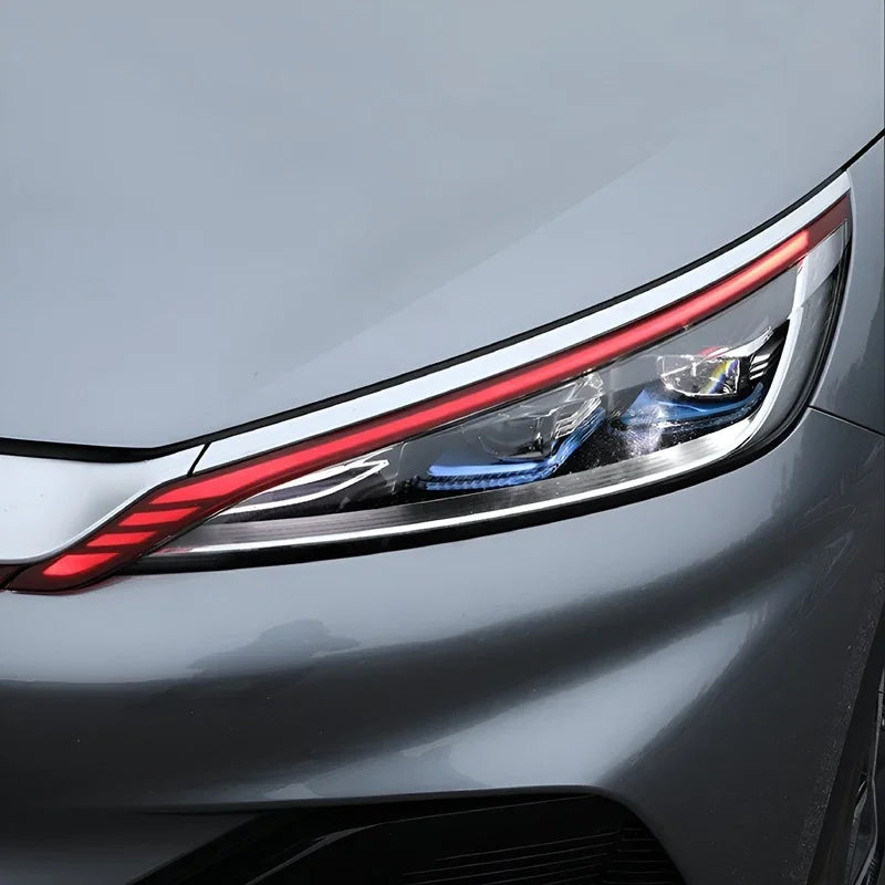Close-up view of a sleek grey car headlight with integrated red LED accent lighting.