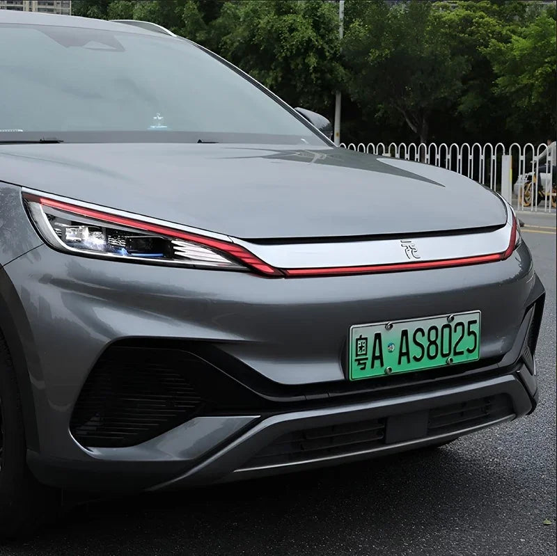 Front view of a grey BYD electric vehicle featuring sleek headlights and a green license plate.