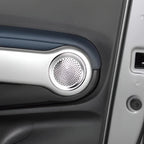 Silver metallic circular speaker grille integrated into a dark grey car door panel.