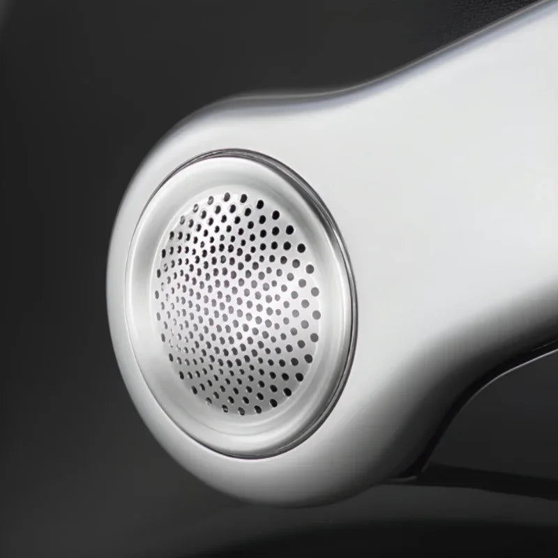 Close-up of a silver metallic speaker grille on a sleek automotive interior component.