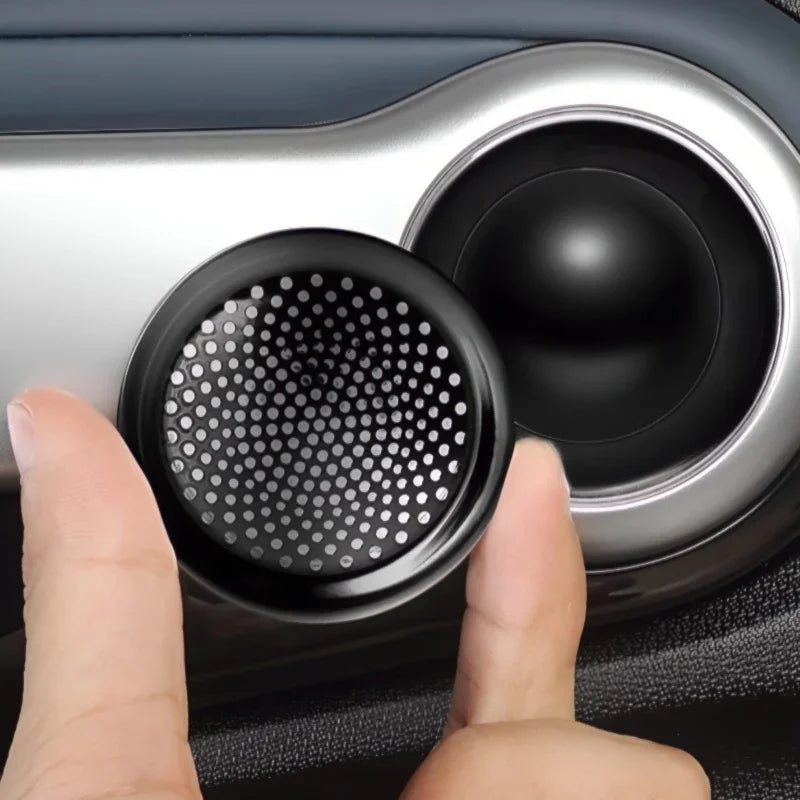 Hand holding a black circular mesh vent cover for a car interior accessory.