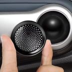 Hand holding a black circular mesh vent cover for a car interior accessory.
