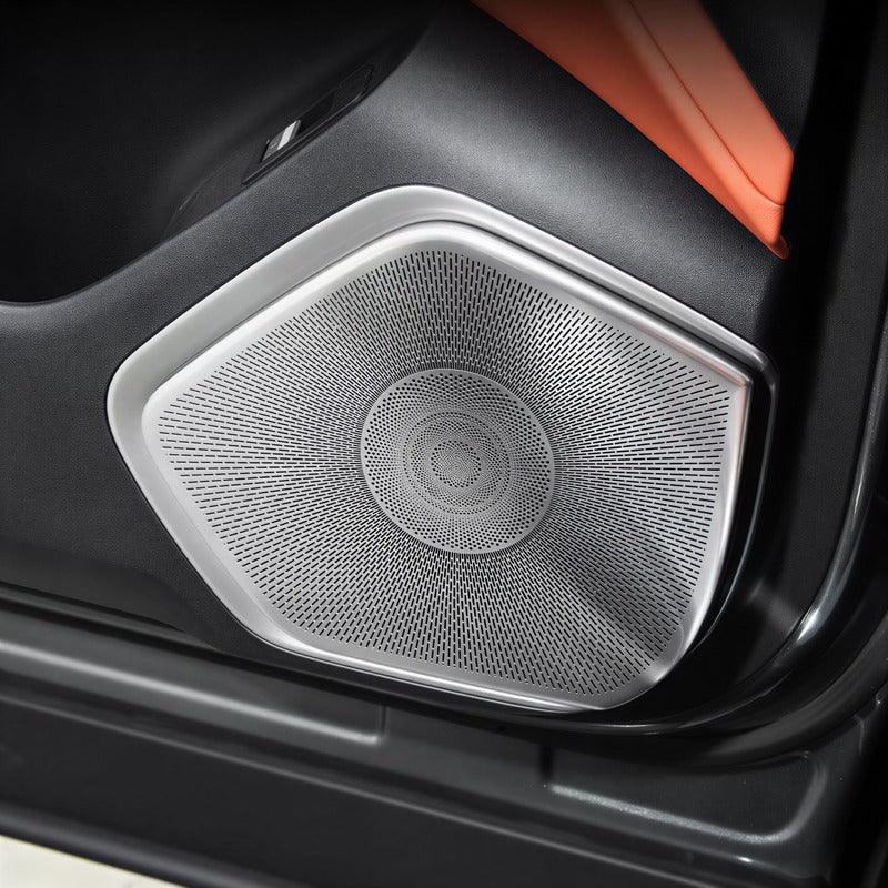 Silver metallic speaker grille cover for car door interior with perforated design