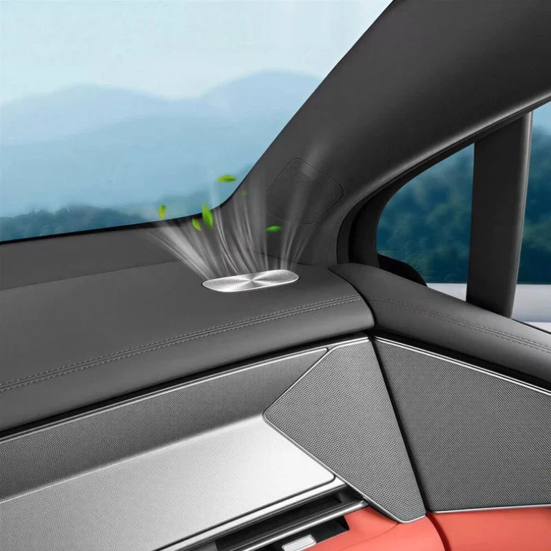Sleek silver metallic car air freshener emitting fragrance on a black leather dashboard.