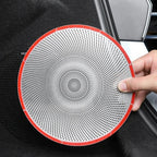 A white circular perforated metal speaker grille with a red rim held by a hand.