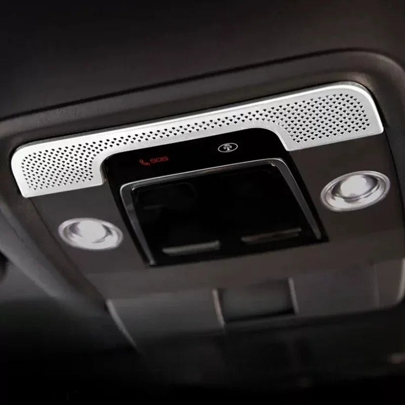 Close-up of a sleek black car roof console featuring a silver perforated grill and SOS button.