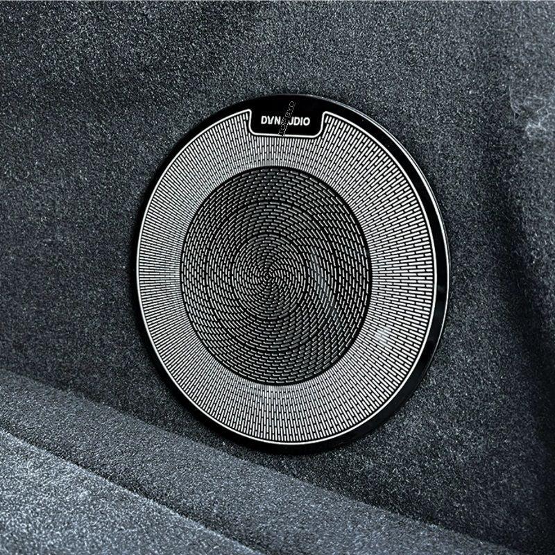 Black circular Dynaudio car speaker grille with a fine metallic mesh pattern.