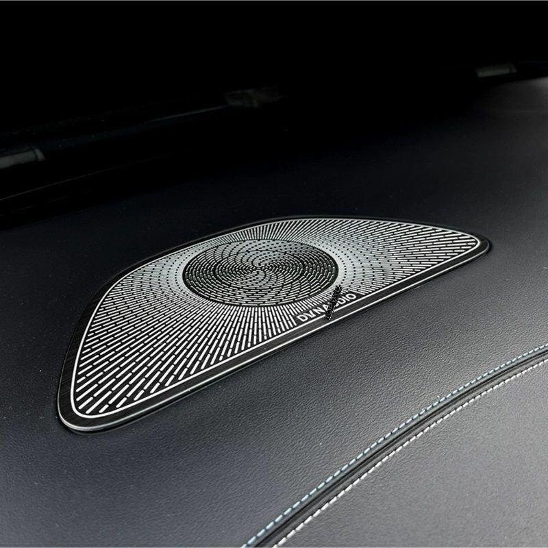 Black textured premium speaker grille with silver concentric ring design on leather interior.