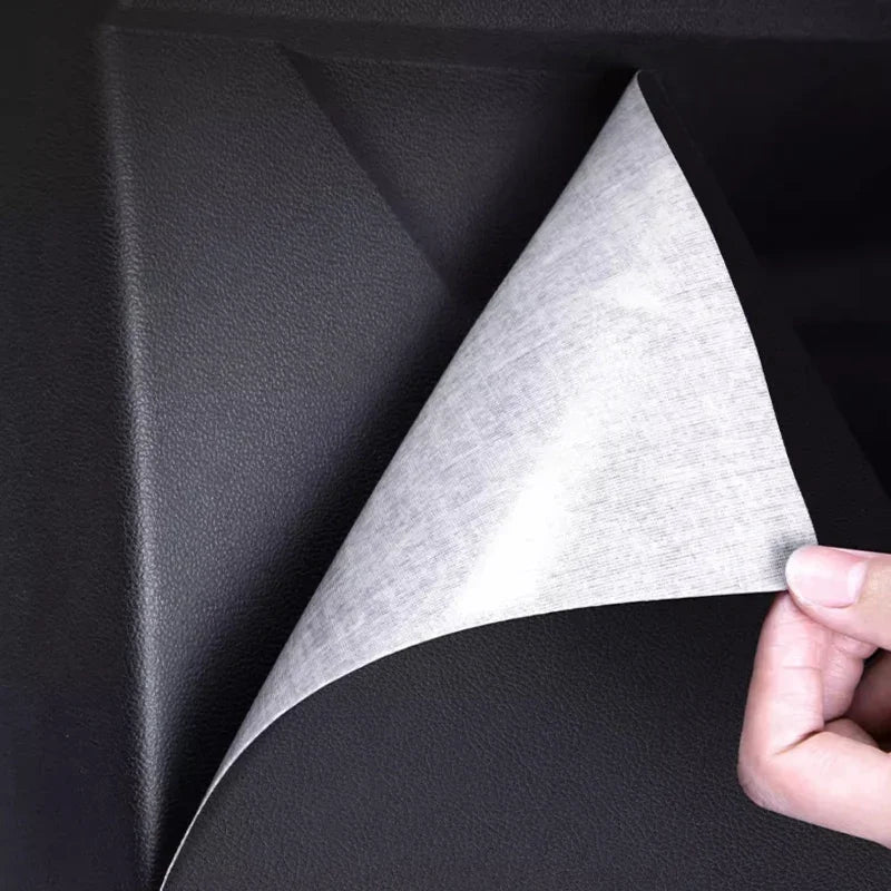 Black textured faux leather car interior protector with white adhesive backing being peeled.