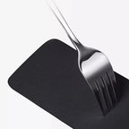 Durable black faux leather car mat protecting against scratches from a metal fork.