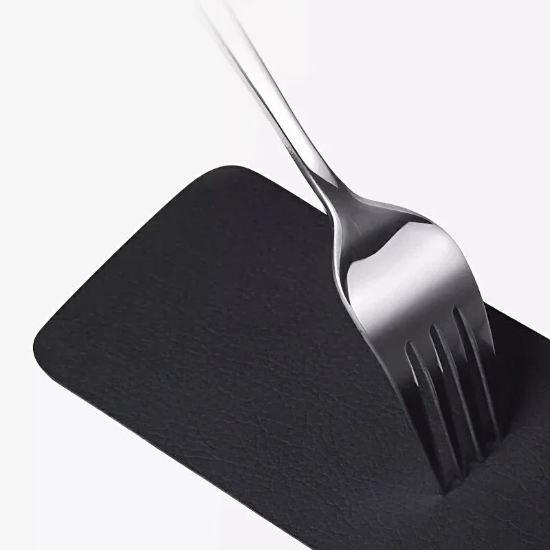 Durable black faux leather car mat protecting against scratches from a metal fork.