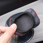 Black leather car door speaker cover with red contrast stitching and protective felt lining.