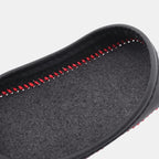 Close-up of a black textured car floor mat with red decorative stitching.