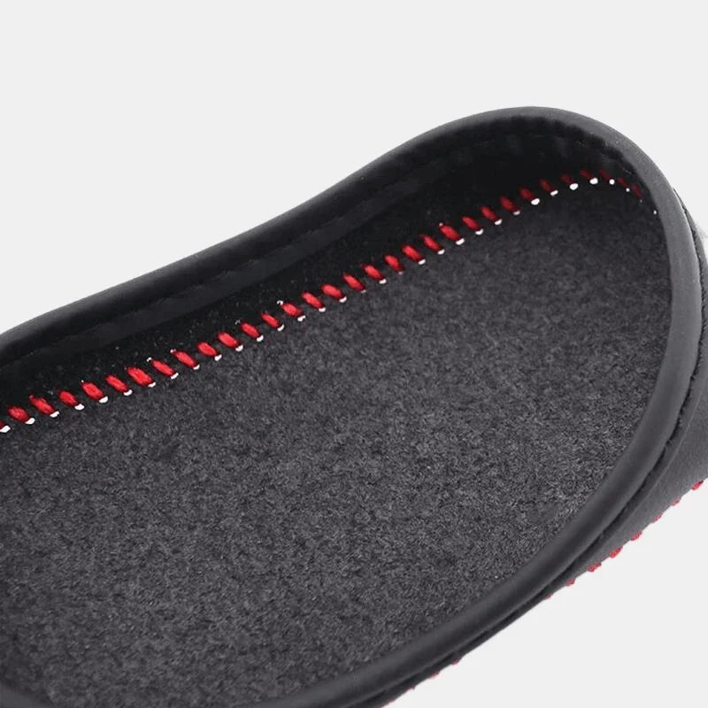 Close-up of a black textured car floor mat with red decorative stitching.
