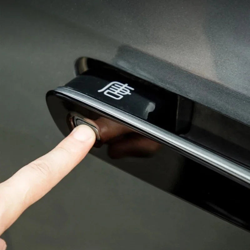 Close-up of a finger pressing a glossy black door handle button with a white Chinese character.