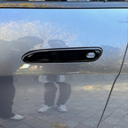 Glossy black door handle cover installed on a silver car, featuring a sleek, durable finish.