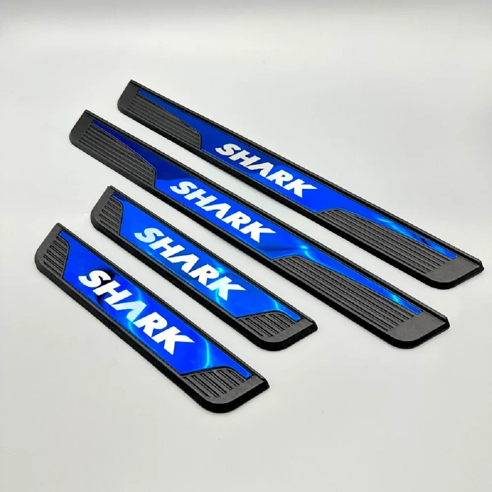 Set of four blue and black metal car door sill protectors with 'SHARK' lettering.