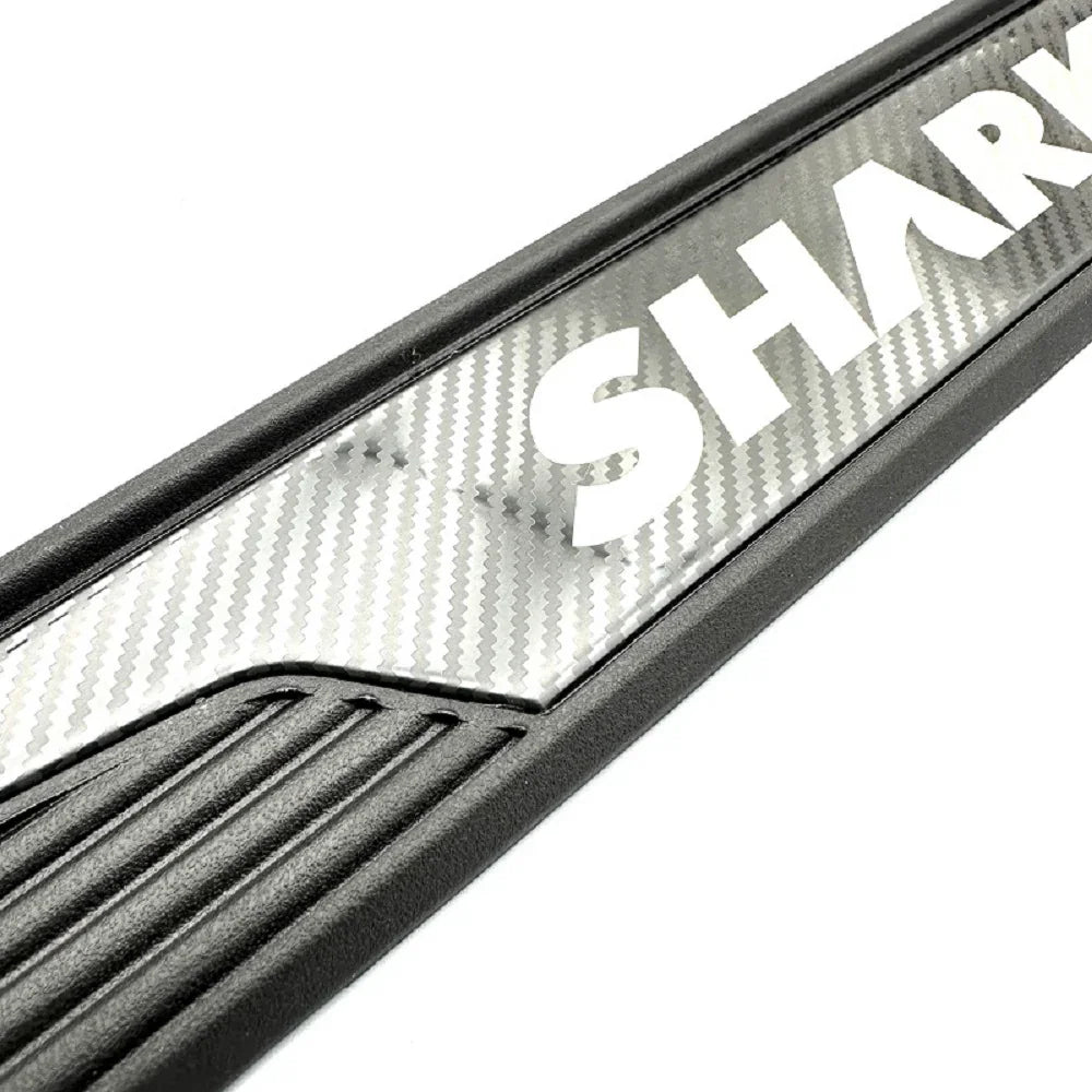 Close-up of a black car door sill protector featuring a silver carbon fiber pattern and SHARK branding.