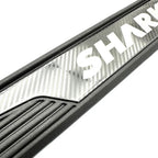 Close-up of a black car door sill protector featuring a silver carbon fiber pattern and SHARK branding.