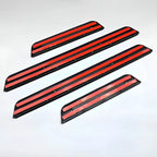 Set of black durable plastic car door sill protectors with vibrant red accent stripes.
