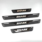 Four black and silver metal SHARK car door sill protectors with a sleek, modern design.