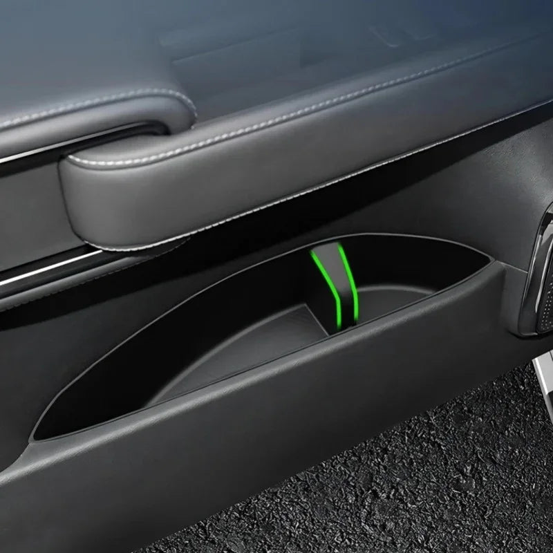 Black leather door panel with a custom-fit interior storage compartment featuring green trim.