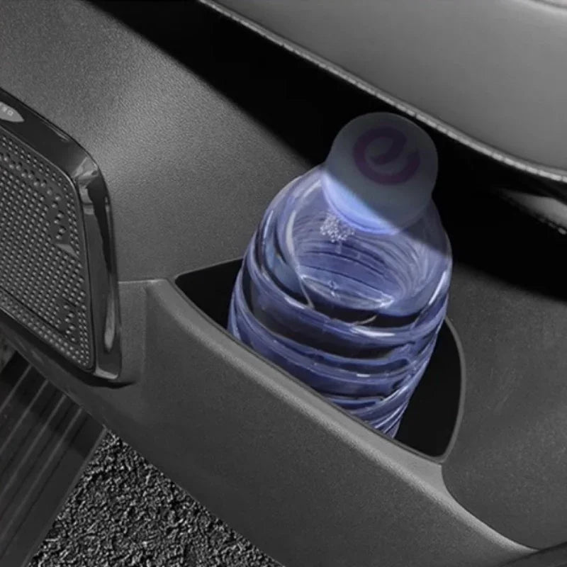 Black matte plastic car door pocket holding a clear plastic water bottle.