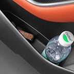 Black textured car center console storage compartment holding a key fob and water bottle.