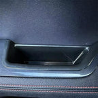Black textured leather door pocket storage compartment with sleek plastic trim.