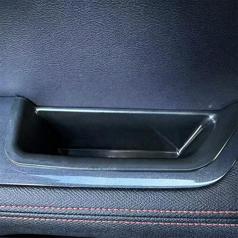 Black textured leather door pocket storage compartment with sleek plastic trim.