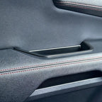 Premium black textured leather car door panel with elegant red contrast stitching.