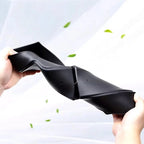 Flexible black TPE car floor mat being bent to demonstrate durable and resilient material.