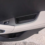 Close-up of a grey car door panel featuring a storage compartment and door handle mechanism.