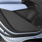 Black textured interior door panel with integrated speaker grille and light blue leather trim.