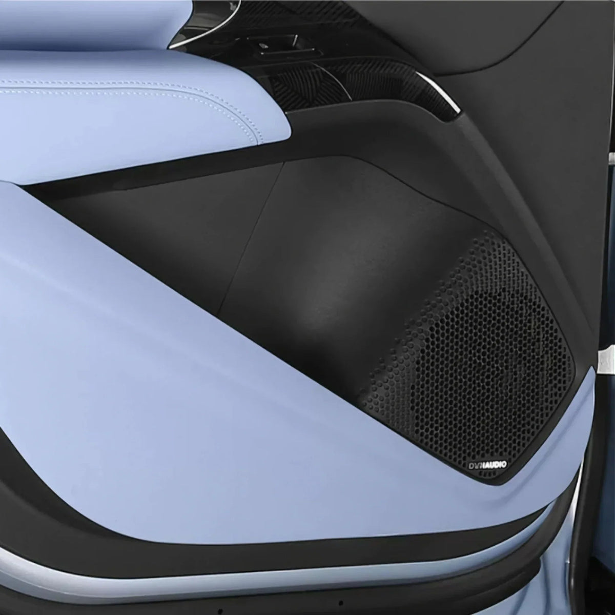 Close-up of a luxury car interior with light blue leather upholstery and a black Dynaudio speaker grill.