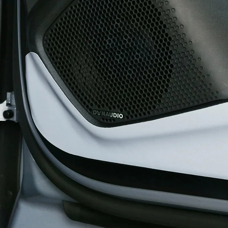 Black Dynaudio speaker grille with a sleek white trim panel installed on a car door.