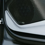 Black Dynaudio speaker grille with a sleek white trim panel installed on a car door.