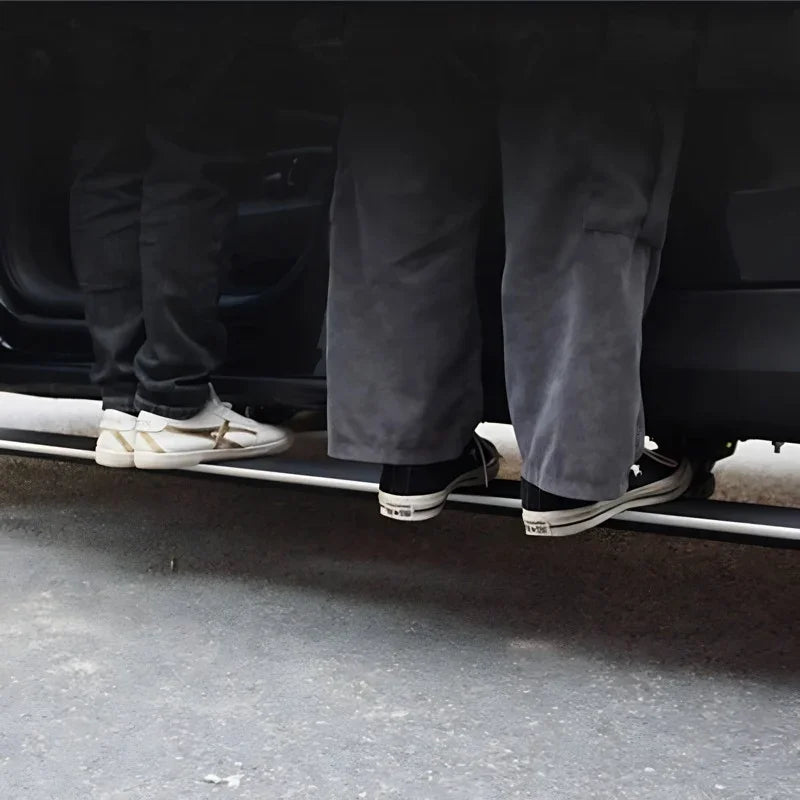 A person wearing grey cargo pants and black sneakers standing next to a car door sill protector.