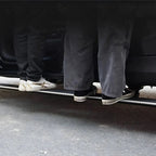 A person wearing grey cargo pants and black sneakers standing next to a car door sill protector.