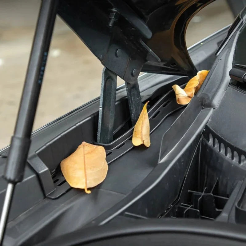 Black durable plastic cowl vent cover protecting car components from fallen dry leaves.