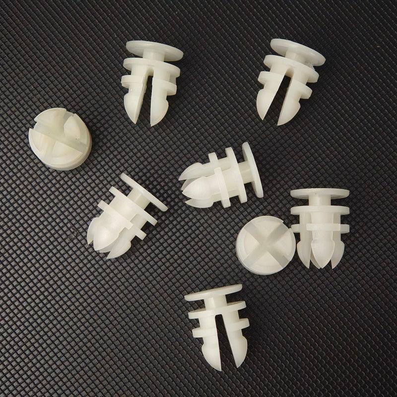 Set of white plastic automotive expansion rivets on a dark textured surface