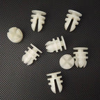 Set of white plastic automotive expansion rivets on a dark textured surface