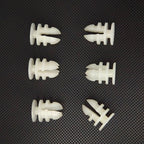 Six white plastic expansion wall plugs for automotive accessories on a textured black surface