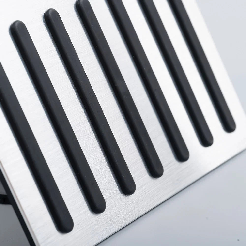 Close-up of a brushed silver metal pedal pad with non-slip black rubber strips.