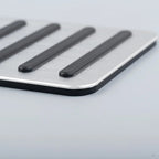 Close-up of a silver brushed aluminum car pedal pad with anti-slip black rubber strips.