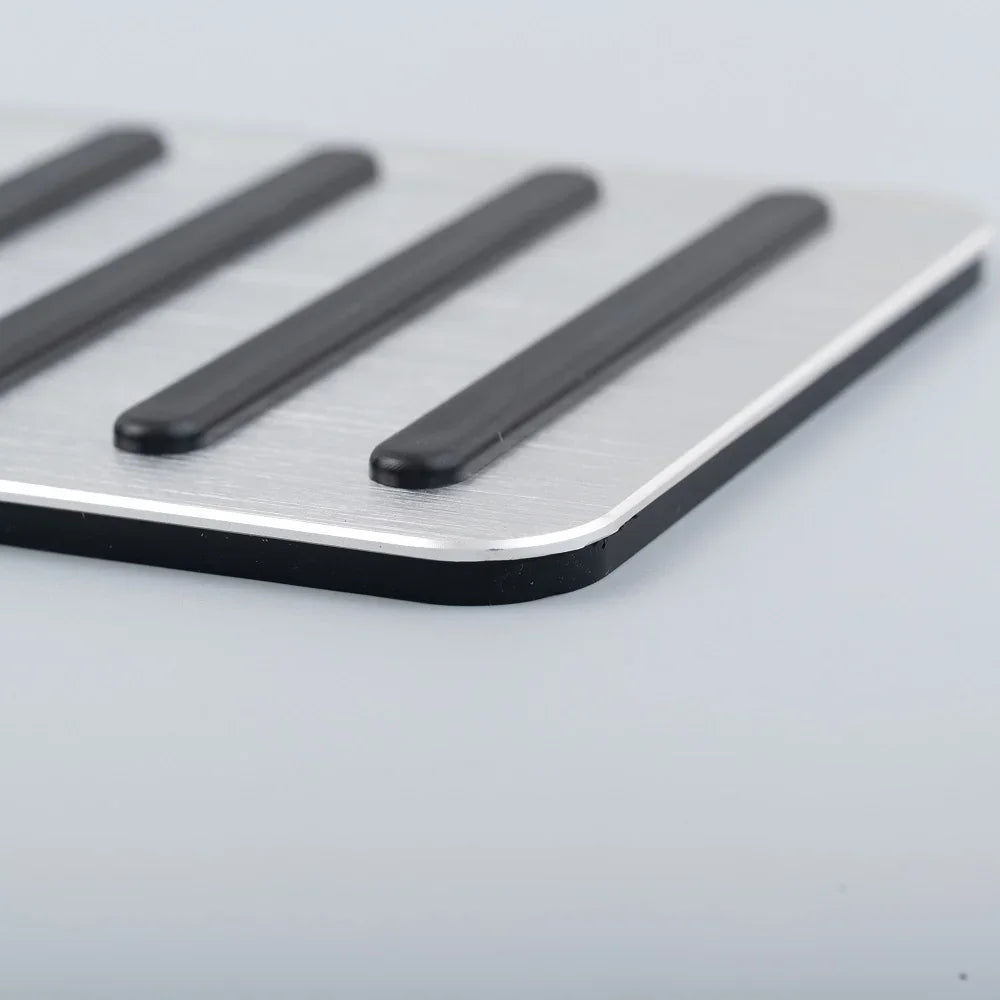 Close-up of a silver brushed aluminum car pedal pad with anti-slip black rubber strips.